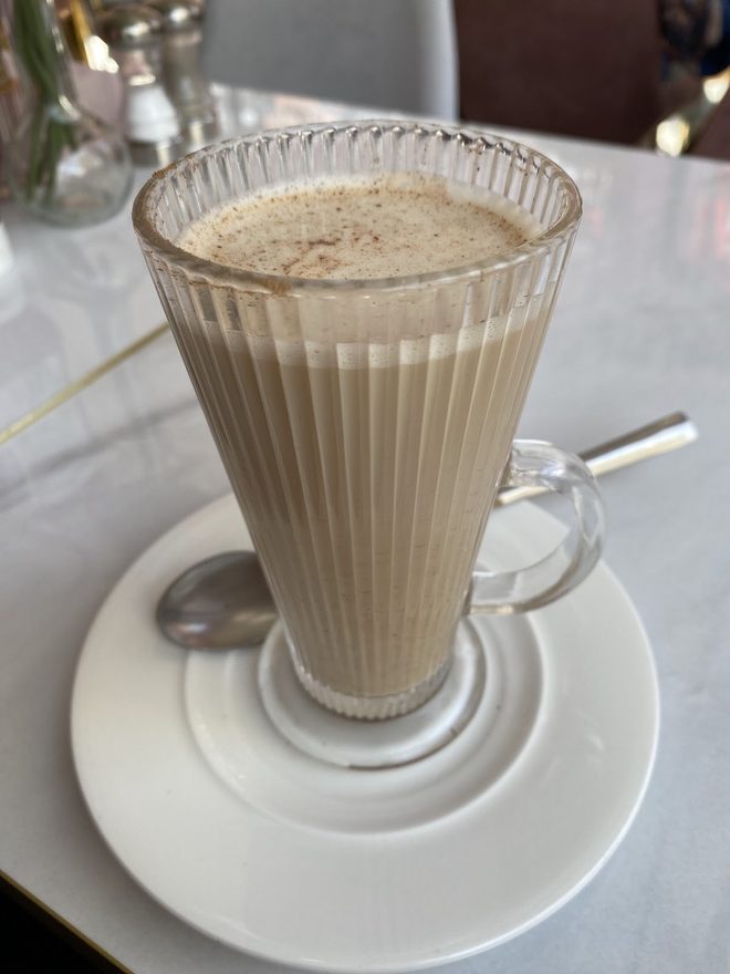A tall fluted latte glass on a saucer.